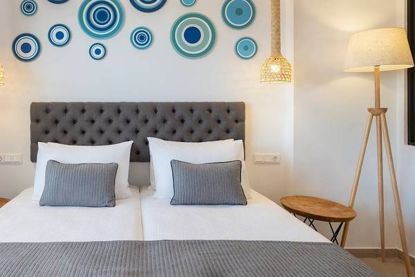 Doppelzimmer im Kalidon Panorama Hotel mit zwei Betten, Kissen, Decken, Nachttischen und dekorativen Kreisen an der Wand.
