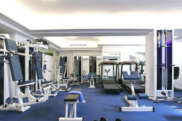 Fitnessstudio im Naxos Resort Beach Hotel mit verschiedenen Trainingsgeräten und einer blauen Trainingsfläche.