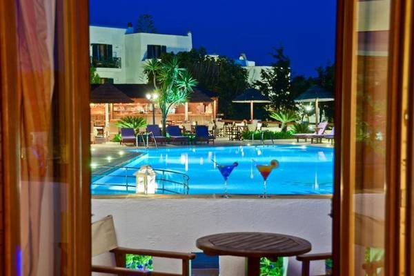 Nachtansicht des Poolbereichs des Naxos Resort Beach Hotel mit gefüllten Gläsern und Loungestühlen.