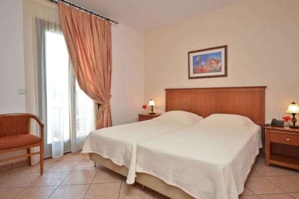 Zwei Betten im Naxos Resort Beach Hotel Zimmer mit weißem Bettzeug, Lampen und einem Bild an der Wand.