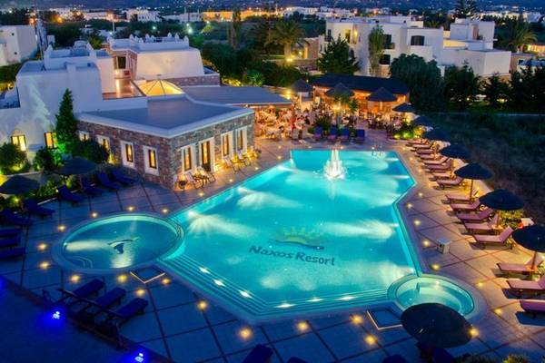Naxos Resort Beach Hotel bei Nacht mit Pool und umliegenden Gebäuden, beleuchtet.