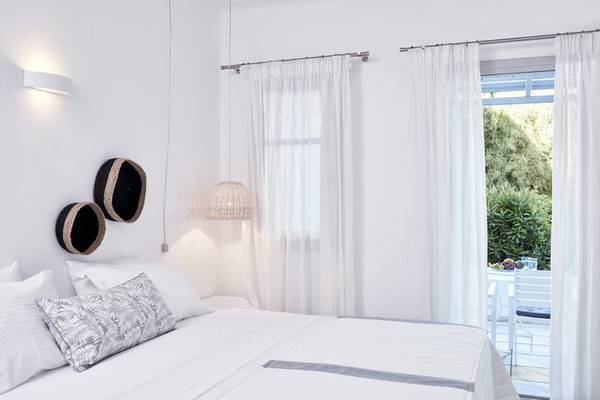 Schlafzimmer im Mr and Mrs White Paros Hotel mit weißen Möbeln und Vorhängen.