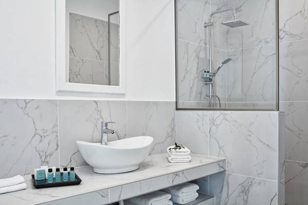 Badezimmer im Mr and Mrs White Paros Hotel mit Marmorfliesen, Waschbecken und Dusche