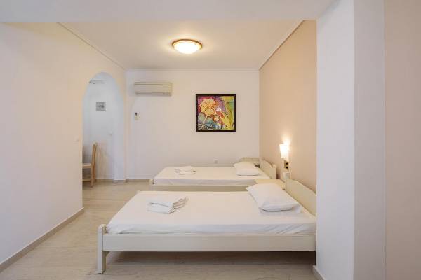 Ein Schlafzimmer im Proteas Hotel mit zwei weißen Betten, weißem Laken, Kissen und einem Gemälde an der Wand.