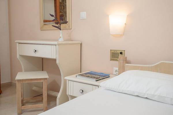 Ein Schlafzimmer im Proteas Hotel mit Bett, Nachttisch, Stuhl und Schreibtisch.