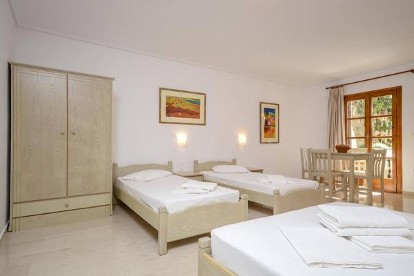 Drei Betten in einem Schlafzimmer im Proteas Hotel mit weißen Laken und Kissen, ein Schrank und Bilder an der Wand.