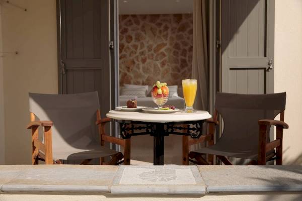 Frühstückstisch auf dem Balkon der Proteas Hotel & Suites mit Obst und Getränken.