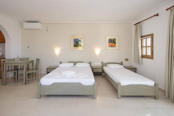 Schlafzimmer im Proteas Hotel mit zwei Betten, Tisch und Stühlen neben einem Fenster.