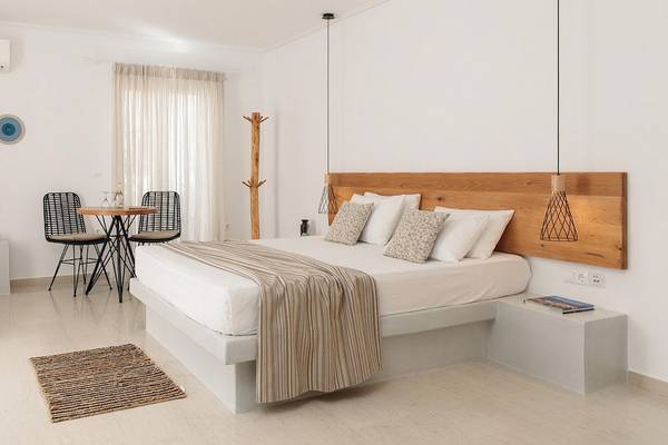 Schlafzimmer im Proteas Hotel & Suites mit weißem Bett, Tisch und Stühlen.