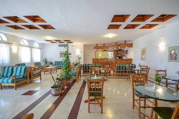 Die Lobby des Proteas Hotel & Suites mit Möbeln, Tischen, Stühlen und Pflanzen.