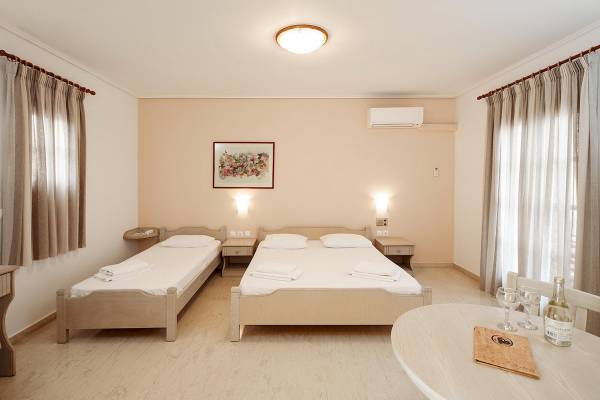 Zimmer im Proteas Hotel & Suites mit zwei Betten, Nachttischen, Klimaanlage und Gemälde an der Wand.