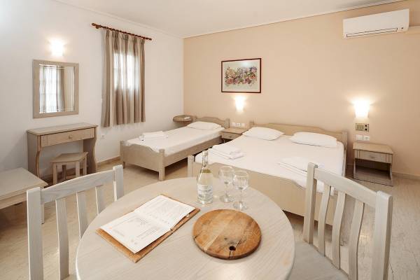 Schlafzimmer im Proteas Hotel & Suites mit zwei Betten, einem Tisch, einem Weinglas und einem Buch.