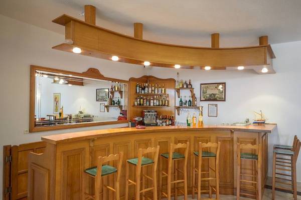 Rezeption und Bar im Proteas Hotel & Suites mit hölzerner Einrichtung und grünen Stühlen.