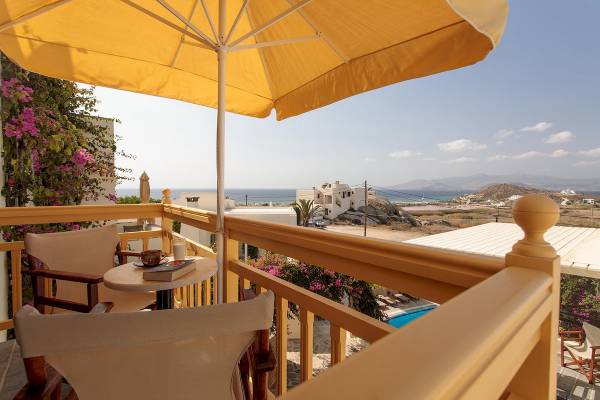 Proteas Hotel & Suites Balkon mit Blick auf das Meer und einen Tisch mit einem Buch und einer Tasse.