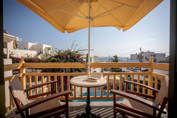 Auf dem Balkon des Proteas Hotel & Suites mit einem Schirm, einem Tisch und einem Buch.