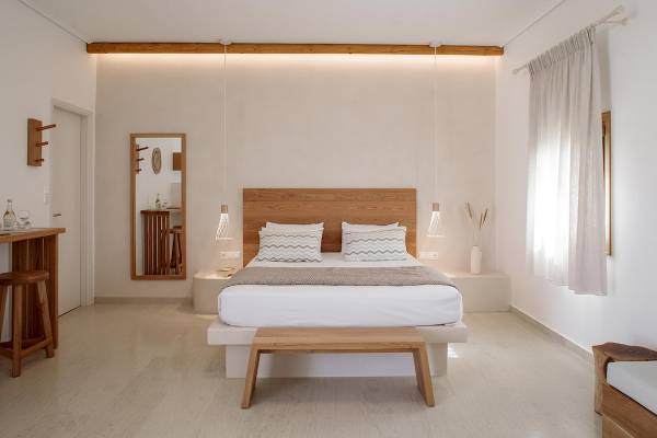 Schlafzimmer im Proteas Hotel & Suites mit weißem Bett, Holzkopfteil und hölzerne Möbel.