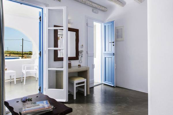 Innenraum des Cycladic Islands Hotel & Spa mit weißen Wänden, blauen Türen und Möbeln.