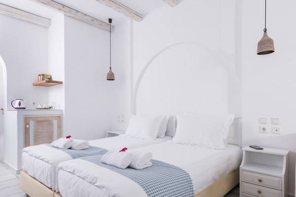 Doppelbettzimmer im Cycladic Islands Hotel & Spa mit weißen Wänden, zwei Betten, und Dekor.