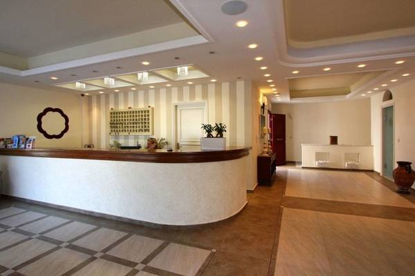 Empfangsbereich des Aegean Palace Hotels mit Rezeptionstresen, Pflanzen und moderner Inneneinrichtung.