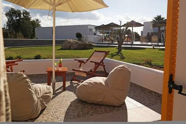 Außenbereich des Aegean Palace Hotels mit Loungestühlen, Kissen und Sonnenschirmen auf der Terrasse.