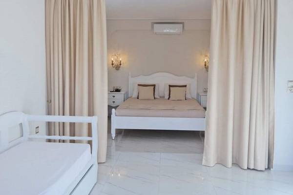 Schlafzimmer im Aegean Palace mit Doppelbett, Nachttischen und großen Vorhängen.