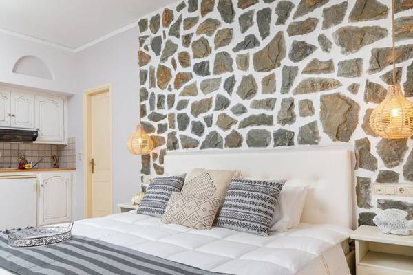 Schlafzimmer mit Steinwand und Bett, Kissen, Decken und Nachttisch