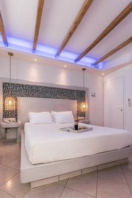 Schlafzimmer im Mikri Vigla Hotel mit weißen Möbeln, Bett und Leopardenmuster an der Wand.