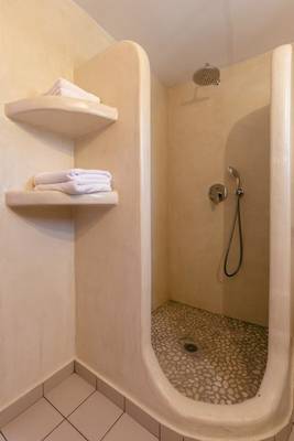 Dusche im Mikri Vigla Hotel mit zwei Regalen und Handtüchern.