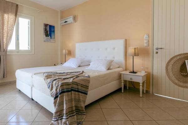 Doppelbettzimmer im Mikri Vigla Hotel mit beigefarbenen Wänden und Fliesenboden.