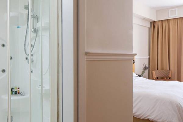 Ein Schlafzimmer im Lagos Mare Hotel mit einer Dusche und einem Bett.