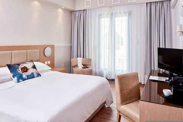 Hotelzimmer im Lagos Mare mit Bett, Fernseher und Schreibtisch.