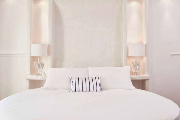 Das Schlafzimmer im Lagos Mare Hotel mit weißen Wänden, einem großen Bett und zwei Nachttischen.