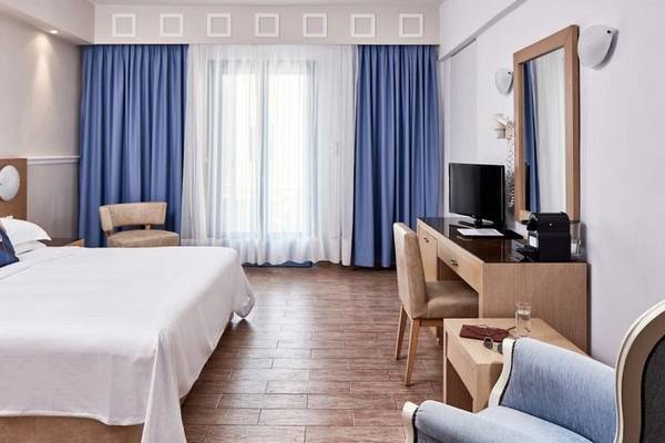 Innenansicht eines Zimmers im Lagos Mare Hotel mit Doppelbett, Schreibtisch und modernen Möbeln.