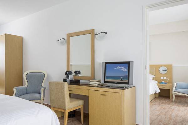 Innenansicht eines Hotelzimmers im Lagos Mare mit Schreibtisch, Fernseher, Stühlen und Spiegel.