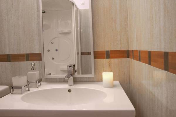Badezimmer im Lagos Mare Hotel mit weißem Waschbecken und Spiegel.