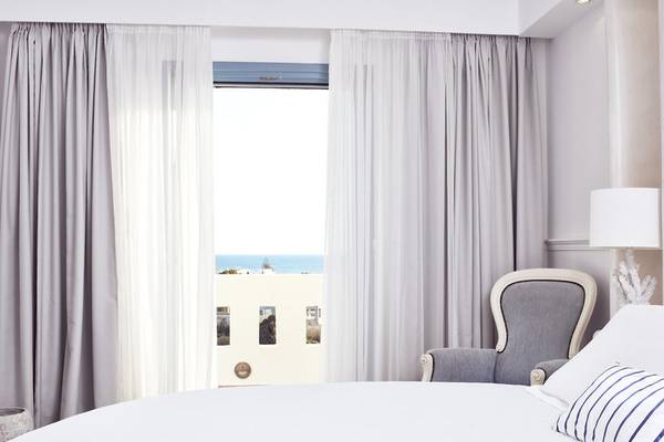 Ein Hotelzimmer im Lagos Mare mit Blick auf das Meer durch ein offenes Fenster.