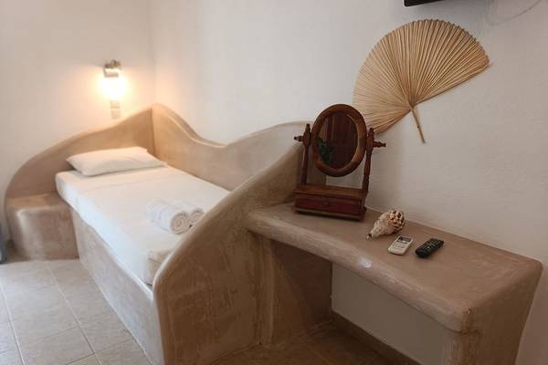 Ein Bett im Hotelzimmer des Naxos Summerland Resorts mit einem Tisch, Spiegel und anderen Gegenständen.
