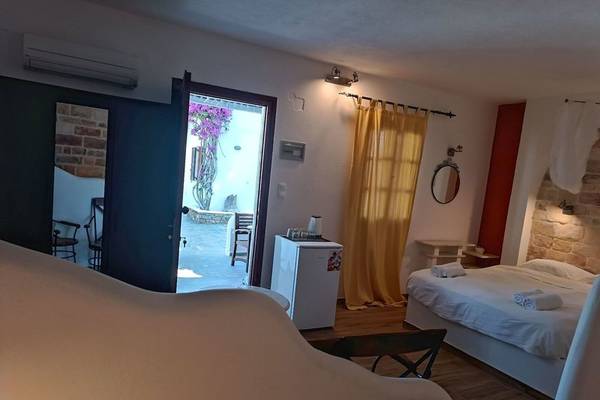 Innenansicht eines Hotelzimmers im Naxos Summerland Resort mit Bett, Kühlschrank und Balkonzugang