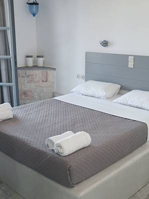 Schlafzimmer mit Bett, Kopfteil, zwei weissen Kissen und Handtüchern, Naxos Summerland Resort