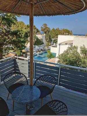 Ein Balkon mit Tisch und Schirm im Naxos Summerland Resort Hotel mit Blick auf den Pool.