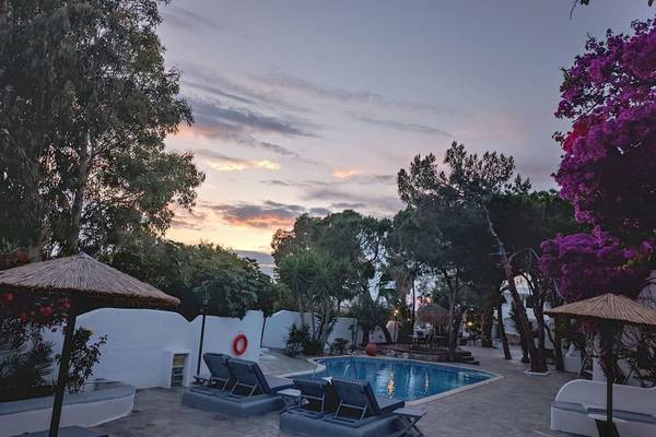 Nachtsicht auf den Poolbereich im Naxos Summerland Resort mit Lounge-Liegestühlen und Sonnenschirmen.