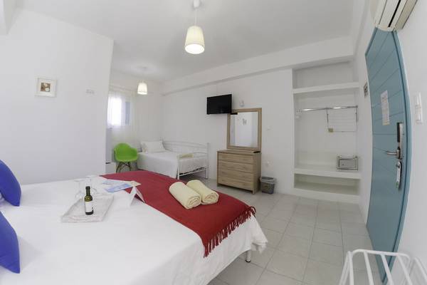 Innenansicht eines Zimmers im Amaryllis Paros Beach Hotel mit weißen Wänden, einem Doppelbett und einem Schlafsofa.