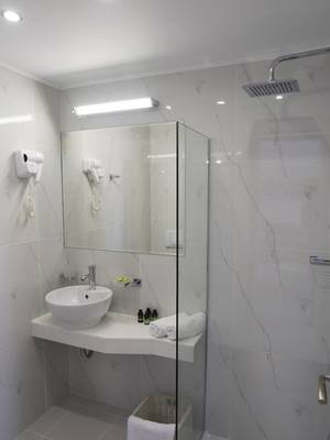 Badezimmer im Amaryllis Paros Beach Hotel mit runden Waschbecken und Glasdusche.