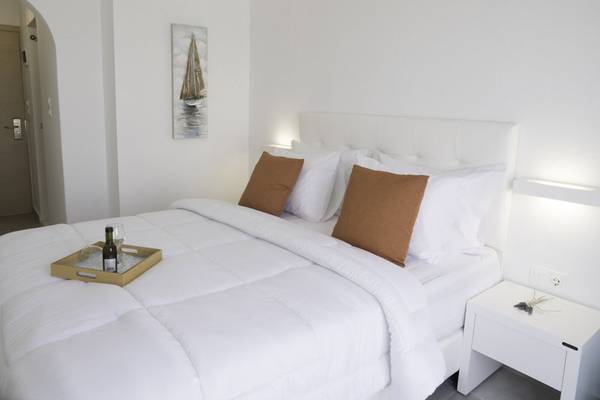 Schlafzimmer im Amaryllis Paros Beach Hotel mit einem Bett, Kissen und einem Nachttisch