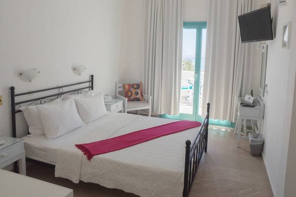 Ein Schlafzimmer im Amaryllis Paros Beach Hotel mit einem Doppelbett, weißem Bettzeug und einem roten Schal.