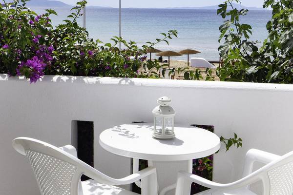 Balkon mit Meerblick vom Amaryllis Paros Beach Hotel mit weißem Tisch, zwei Stühlen und Laterne.