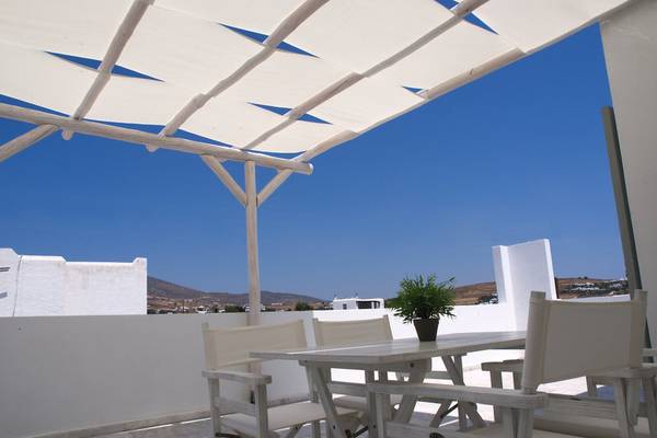 Terrasse des Amaryllis Paros Beach Hotels mit Tisch und Stühlen unter einem Sonnendach.