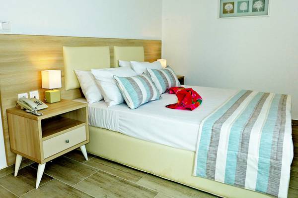 Doppelbett-Zimmer im Amaryllis Paros Beach Hotel mit Nachttisch, Lampe und Bild an der Wand.
