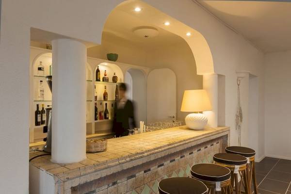 Innenansicht der Bar im Mare Pineta Hotel mit Theke, Stühlen und Lampen.