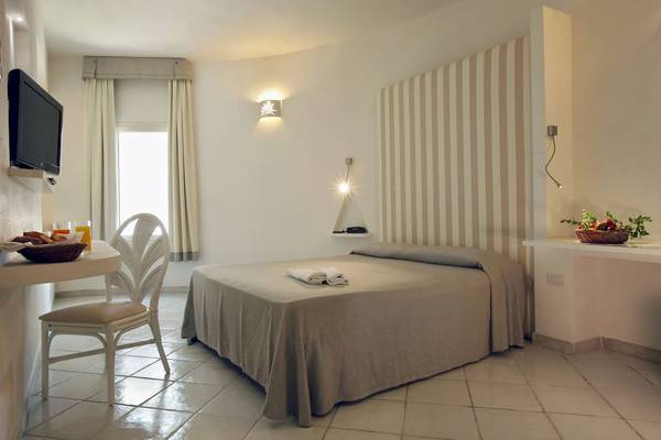 Hotelzimmer im Mare Pineta Hotel mit Bett, Tisch, Fernseher und Obstkorb.